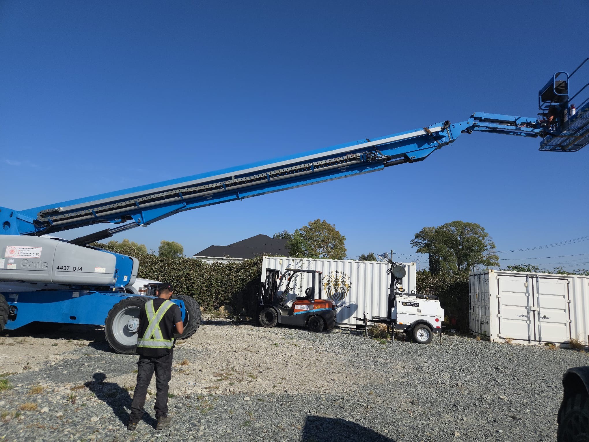 Genie S-125 boom extended in our Surrey yard, with forklift, light tower and containers